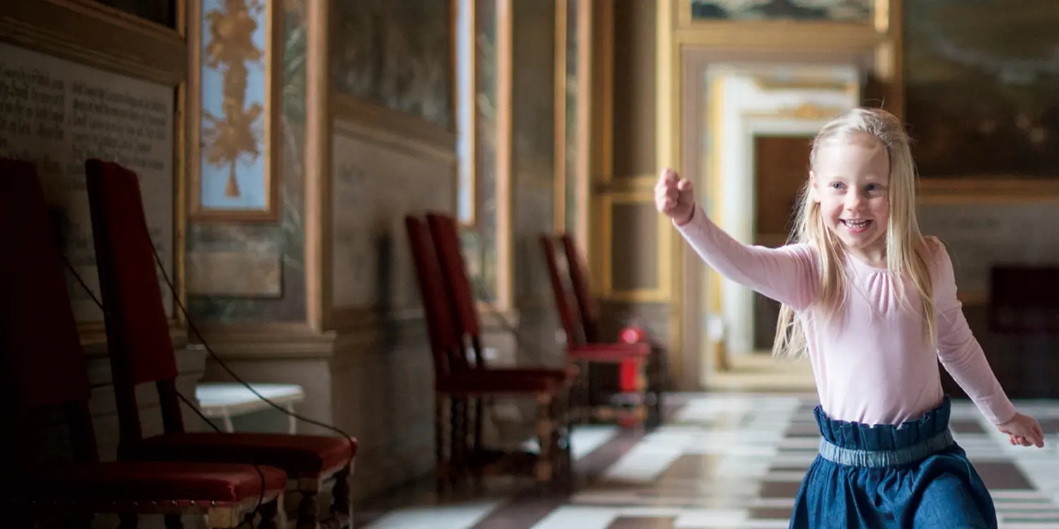 En glad flicka i en sal på Drottningholms slott.